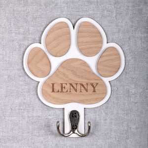May include: White wooden paw print shaped coat hook with a silver hook and the name "LENNY" engraved on the paw print.