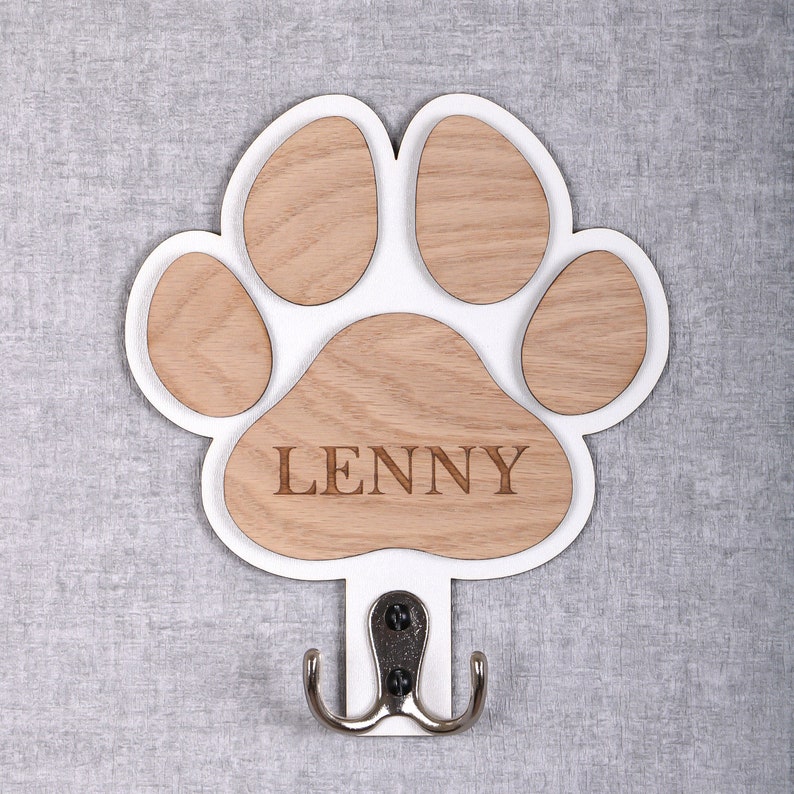May include: White wooden paw print shaped coat hook with a silver hook and the name "LENNY" engraved on the paw print.