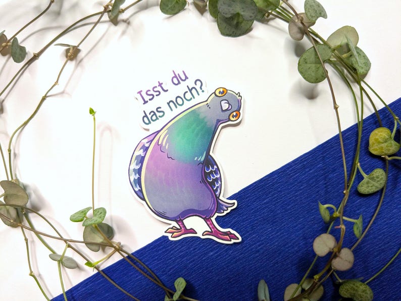 Puede incluir: Una pegatina troquelada que muestra una paloma de dibujos animados con plumas iridiscentes de color p&uacute;rpura, verde y azul. La paloma tiene ojos grandes y muy abiertos y mira por encima del hombro. Sobre el ave, el texto en alem&aacute;n "Isst du das noch?" est&aacute; impreso en una fuente sans-serif de color p&uacute;rpura oscuro.