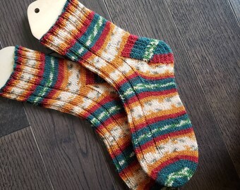 May include: A pair of knitted socks with a colorful striped pattern in shades of orange, red, green, and white. The socks are made with a chunky yarn and have a ribbed texture.