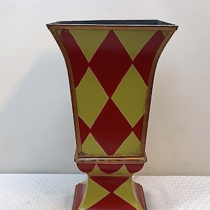 May include: A red and yellow ceramic vase with a diamond pattern. The vase has a wide base and a narrow neck.