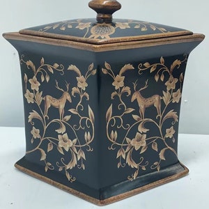 May include: A black ceramic square box with a lid. The box has a gold floral design with deer and a pomegranate on the lid.