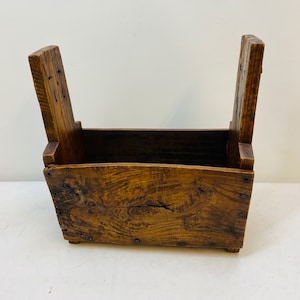 May include: A rustic wooden box with two hinged sides, crafted from reclaimed wood with a natural brown finish. The box has a rectangular shape and is secured with metal nails.