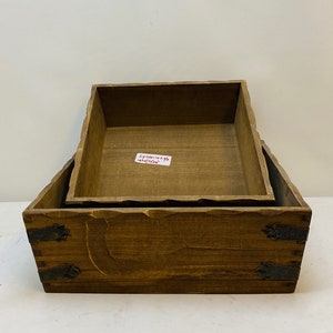 May include: Two wooden boxes, one nested inside the other. The larger box has metal accents on the sides. The smaller box has a handwritten label that reads "12" x 12" x 4.5" 18cm x 18cm x 11cm".