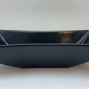 May include: A black ceramic rectangular serving dish with a slightly curved, angled rim.