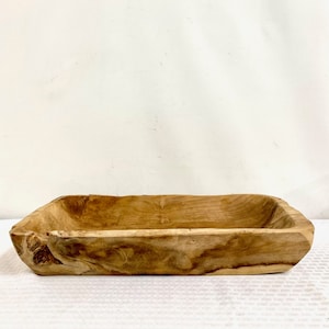 May include: A large, rectangular wooden serving bowl with a natural wood finish. The bowl has a rustic, handcrafted look and is perfect for serving bread, fruit, or other snacks.