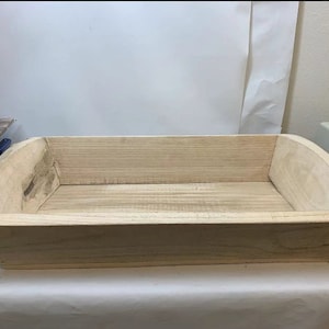 May include: A natural wood rectangular tray with rounded edges. The tray is made of light wood and has a smooth finish.