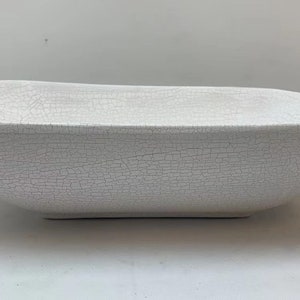 May include: White ceramic bowl with a crackled glaze finish. The bowl is rectangular in shape and has a slightly rounded bottom.