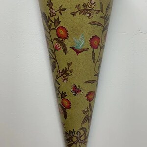 May include: A green cone-shaped wall vase with a floral pattern and gold accents. The vase features a bird and butterfly design.