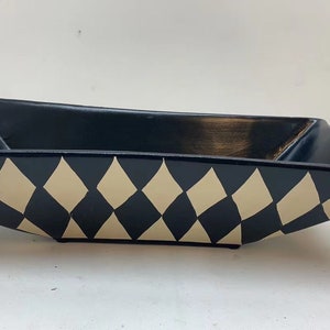 May include: A black and white ceramic serving dish with a diamond pattern. The dish is rectangular and has a slight curve to the sides.