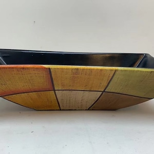 May include: A rectangular ceramic serving bowl with a black rim and a geometric pattern of yellow, orange, and brown squares.
