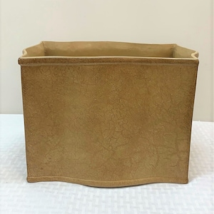 May include: A rectangular planter made of terracotta with a textured, crackled finish. The planter has a slightly curved bottom and a slightly flared top.