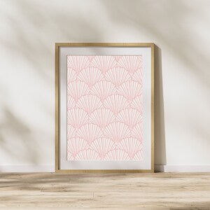 May include: A framed print with a geometric pattern of pink fan shapes on a white background. The frame is made of light wood.