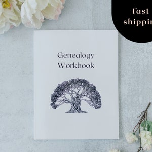 May include: A white Genealogy Workbook with the title and a tree illustration in black ink. The words "fast shipping" are in a black circle in the upper right corner. The book is surrounded by white flowers and greenery.