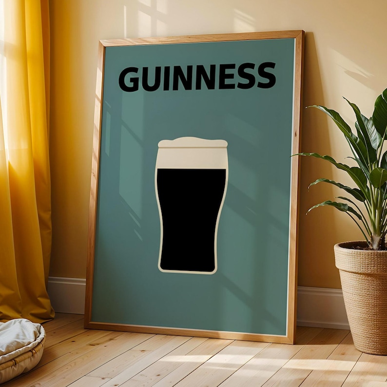 May include: A framed poster with a minimalist design of a pint of Guinness stout. The black beer contrasts with the white foam, set against a teal background. The word "GUINNESS" is printed in bold black letters at the top.