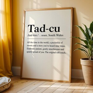 May include: A framed wall art print featuring the word Tad-cu, defined as a noun from South Wales. The text reads: All the time in the world, a pocketful of sweets and a story you've heard nine times. Endlessly patient, gently mischievous and quietly proud of you. The original soft touch.