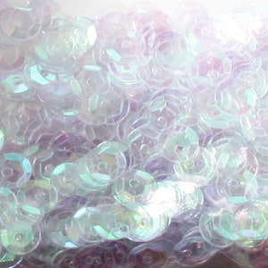 May include: A close-up of iridescent white sequins, perfect for crafting or embellishing clothing and accessories.