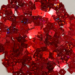 May include: A large pile of red square sequins with a holographic finish. The sequins have a small hole in the center.