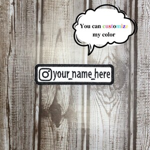 May include: White iron-on patch with black outline featuring an Instagram logo and the text "your_name_here". The patch is on a wood background. A speech bubble above the patch says "You can customize my color".