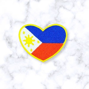 May include: A heart-shaped embroidered patch with the flag of the Philippines. The flag features a white triangle with a yellow sun and three stars, a blue upper stripe, and a red lower stripe. The patch is outlined in yellow.
