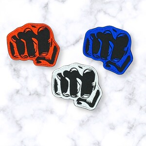 May include: Three embroidered iron-on patches in the shape of a fist. The fist patches are in red, blue, and white.