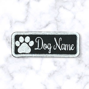 May include: Black rectangular fabric patch with white embroidered paw print and the text "Dog Name".