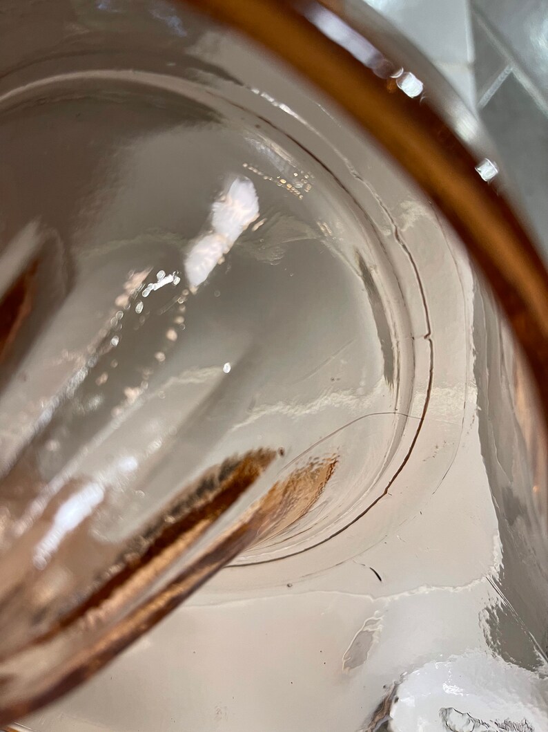 K&ouml;nnte beinhalten: Nahaufnahme des Inneren eines durchsichtigen Glaskrug mit braunem Rand. Das Glas ist leicht strukturiert und hat einen kleinen Riss am Rand.