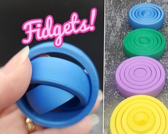 Peut inclure: Un ensemble de quatre jouets sensoriels, chacun avec une couleur et un nombre d'anneaux différents. Les couleurs sont bleu, vert, violet et jaune. Les jouets sont en plastique et sont conçus pour être tournés et retournés.