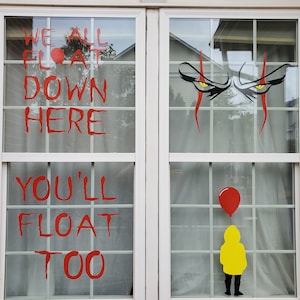 May include: Two windows with red and white lettering that reads "We all float down here you'll float too". The right window has a pair of red eyes with black pupils and a red clown nose. The bottom of the right window has a red balloon and a yellow raincoat.