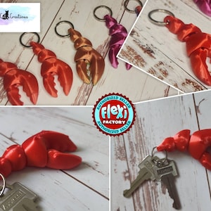 May include: Red lobster claw keychains with silver key rings. The keychains are made of a 3D-printed material. The image also shows a gold and a pink lobster claw keychain. The keychains are from Squirrel Cat Creations.