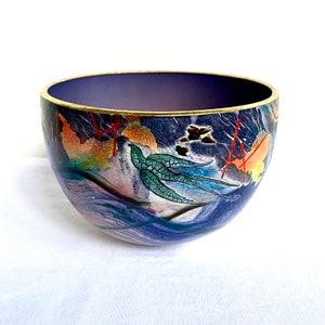 May include: A blue and white ceramic bowl with a gold rim and a painted design of a bird and foliage. The bowl has a purple interior.