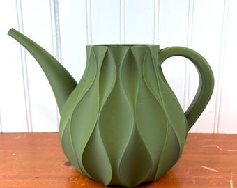 May include: A green watering can with a textured, wavy design. The can has a spout and a handle.