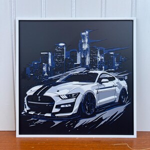 May include: A white Ford Mustang Shelby GT500 with black racing stripes, set against a backdrop of a city skyline at night. The car is facing the viewer and has a blue and white color scheme.