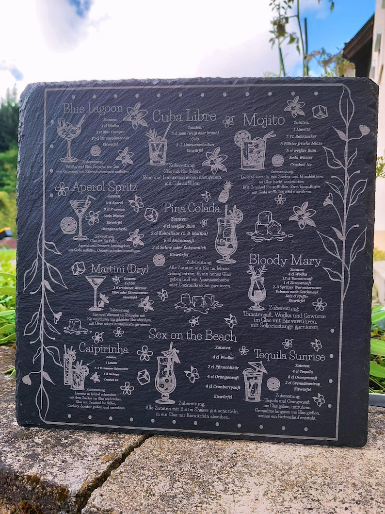 May include: A dark gray slate serving board etched with cocktail recipes, including Blue Lagoon, Mojito, and Pina Colada. The board features detailed illustrations of each drink and their ingredients, with floral accents.