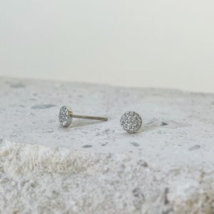 Puede incluir: Un par de pendientes de bot&oacute;n de plata con un dise&ntilde;o redondo de diamantes pav&eacute;.
