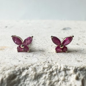 May include: A pair of gold butterfly earrings with red ruby stones.