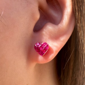 Op de afbeelding: Een paar hartvormige oorbellen met een roze robijn-steen setting. De oorbellen zijn gemaakt van goud en hebben een gepolijste afwerking.