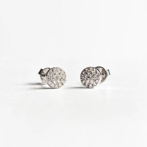 Puede incluir: Un par de pendientes de bot&oacute;n de plata con un dise&ntilde;o redondo de diamantes pav&eacute;.