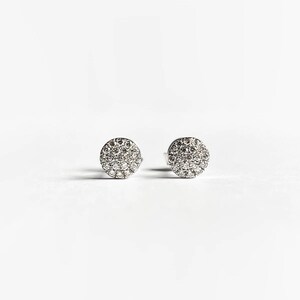 Puede incluir: Un par de pendientes de bot&oacute;n de plata con un dise&ntilde;o redondo de diamantes pav&eacute;.