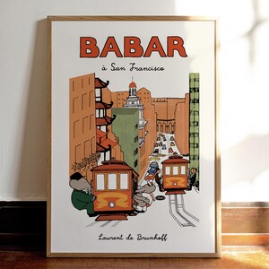Puede incluir: Una impresión artística enmarcada con una colorida ilustración de Babar en San Francisco. La obra representa tranvías, edificios y el texto "BABAR à San Francisco" en naranja y negro. Firmado por Laurent de Brunhoff.