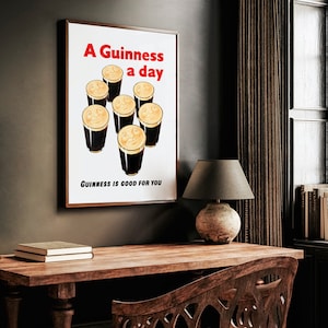 May include: A vintage poster with a brown wooden frame. The poster features a white background with the text "A Guinness a day" in red and black lettering. The poster depicts seven glasses of Guinness beer with smiling faces.