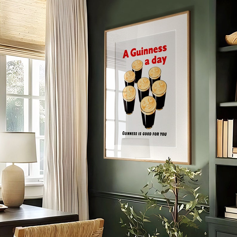 May include: A vintage Guinness poster with a white background and a brown wooden frame. The poster features a cartoon illustration of seven glasses of Guinness with smiling faces. The text on the poster reads "A Guinness a day" and "Guinness is good for you".