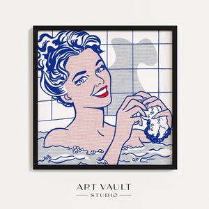 May include: Pop art print of a woman in a bathtub, holding a sponge. The artwork features bold lines and a limited color palette of blue, pink, and red. The print is framed in a black frame and includes the text "ART VAULT STUDIO".