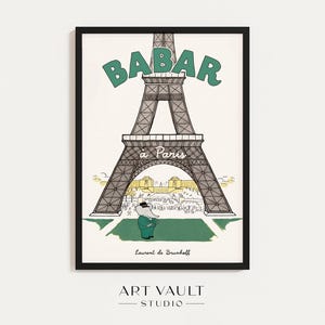 May include: Framed art print featuring the Eiffel Tower with the text "BABAR à Paris" in green. The illustration includes a cartoon elephant in a green suit. The artist's name, Laurent de Brunhoff, is at the bottom.