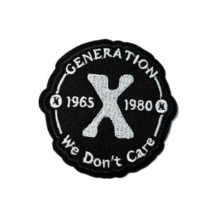 May include: Black and white embroidered patch with the text "GENERATION X We Don't Care" in a circular design. The patch includes the years 1965 and 1980, and a large white "X" in the center.