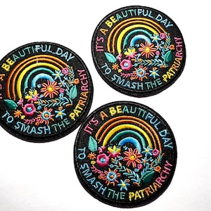 May include: Three round embroidered patches with a black background. Each patch features a rainbow, flowers, and the text "It's a beautiful day to smash the patriarchy" in colorful thread.