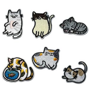 May include: Set of six embroidered cat patches in various poses and colors. Includes a gray tabby cat sleeping, a black and white cat, and a calico cat with a fishbowl. Each patch has a white border.