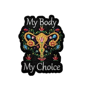 May include: Embroidered patch with the text "My Body My Choice". The patch features a colorful floral design around a stylized uterus in gold, with red, blue, and yellow accents, set against a black background.