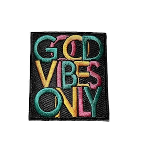 May include: A rectangular black embroidered patch featuring the text GOOD VIBES ONLY in stacked, multi-colored lettering. The letters are stitched in shades of teal, yellow, and pink, creating a vibrant contrast against the solid black background.