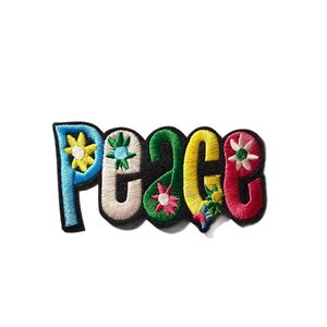May include: An embroidered patch featuring the word PEACE in colorful block letters. The P is blue with a yellow flower, E is beige with a green flower, A is green with a pink flower, C is yellow with small flowers, and E is red with a white flower.